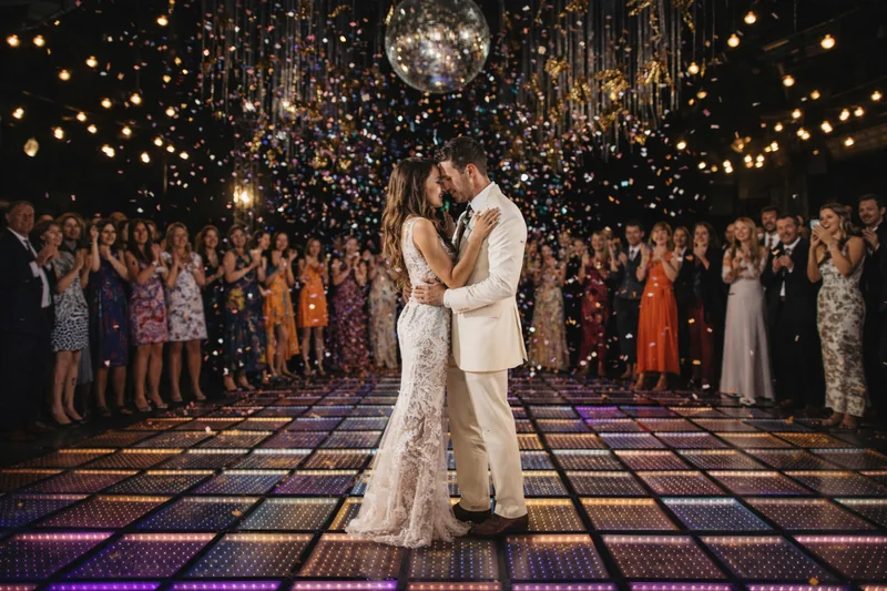 Novios bailando en pista iluminada con confetti, representando los servicios de los DJs más buscados en Chile. 